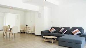 Un salon moderne avec un canapé gris, une table basse ronde et un coin repas comprenant des chaises et une petite table.