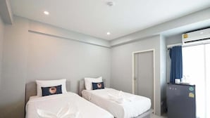 Une chambre d’hôtel avec deux lits, une petite kitchenette et une porte donnant sur une salle de bain.