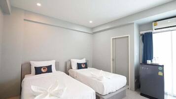 A hotel room with two beds, a small kitchenette, and a door leading to a bathroom.
