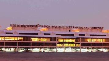 A large, multi-level airport terminal with a prominent sign indicating it is Don Mueang International Airport.