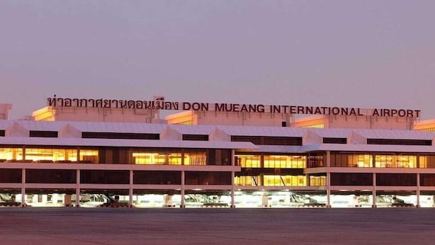 Un grand terminal aéroportuaire à plusieurs niveaux, avec une enseigne bien visible indiquant qu’il s’agit de l’aéroport international de Don Mueang.