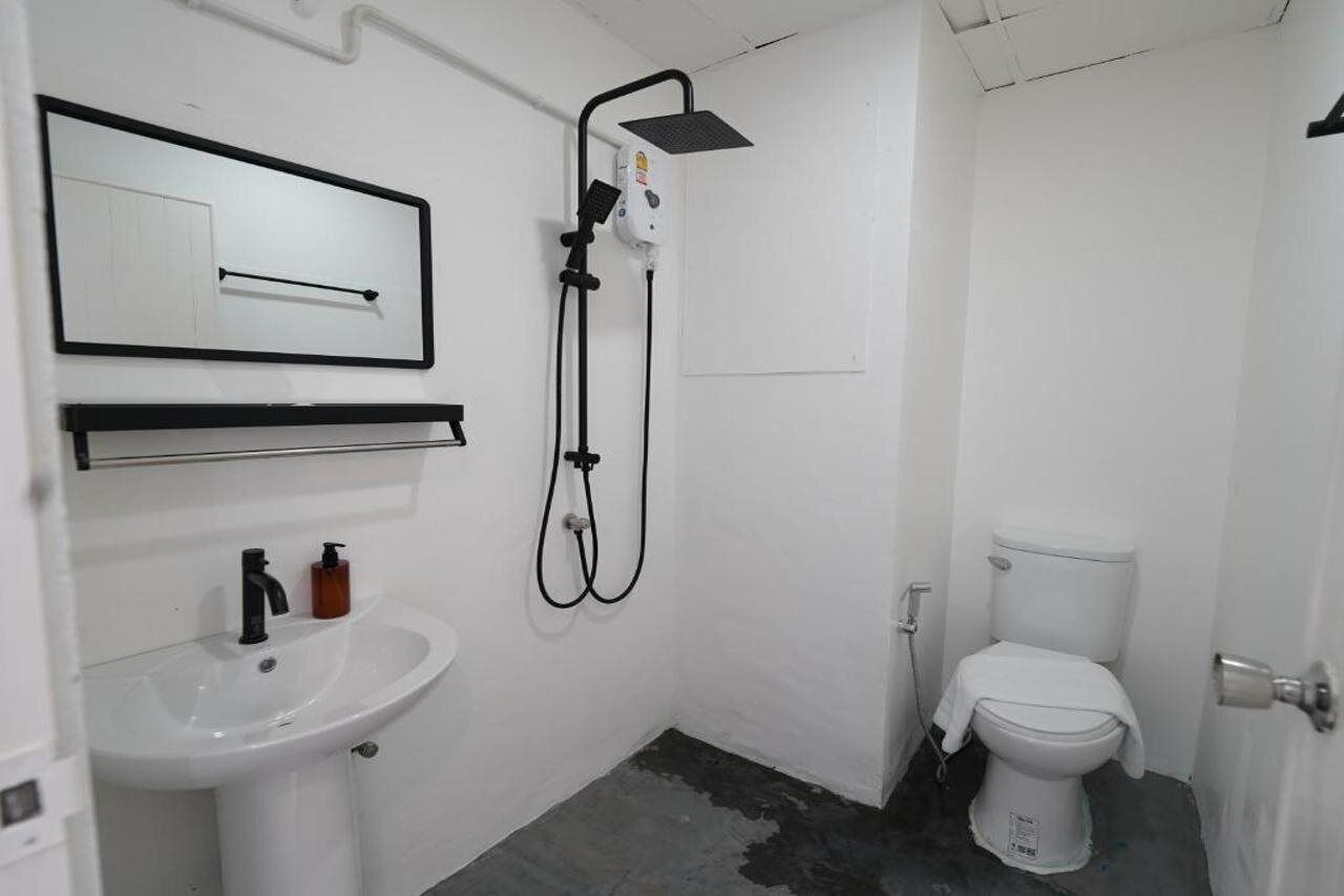 A small, white bathroom with a sink, toilet, and shower.