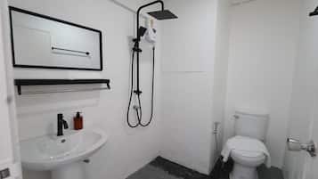 A small, white bathroom with a sink, toilet, and shower.