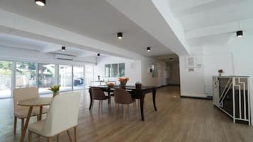 A spacious room with a dining area, large windows, and a view of the outside.