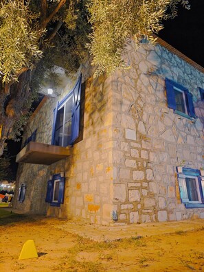 Un edificio de piedra con contraventanas azules y un balcón.