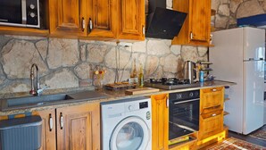 Eine Küche mit Holzausstattung, einer Steinwand, einer Waschmaschine, einem Herd und einem Kühlschrank.