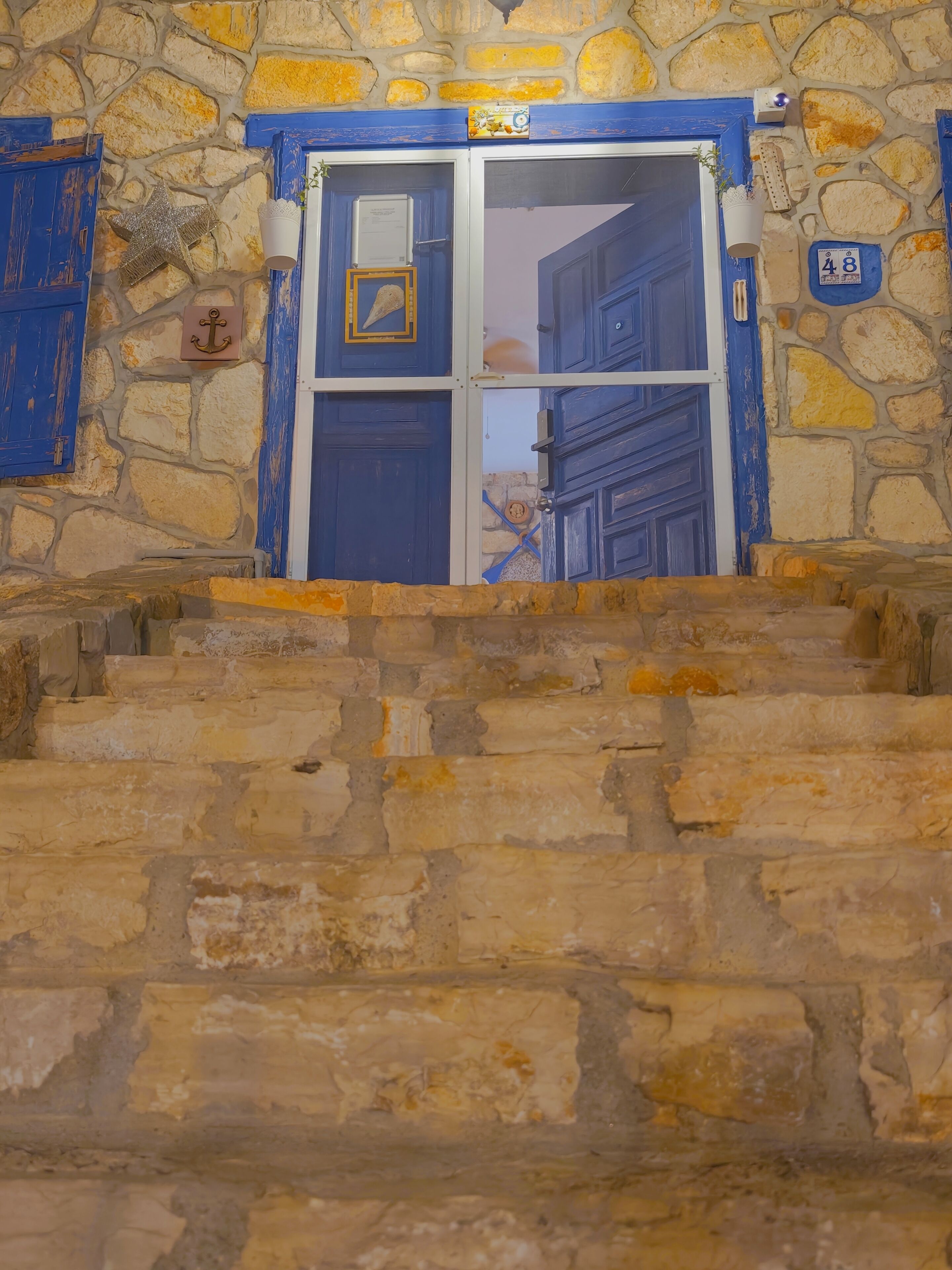 Eine Steintreppe führt zu einer blauen Tür mit einem Schild, das die Zimmernummer 48 angibt.