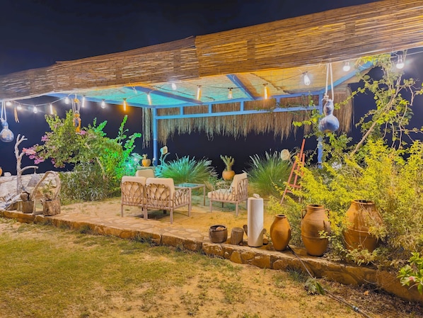 An outdoor seating area with tables and chairs, surrounded by potted plants and decorative vases.