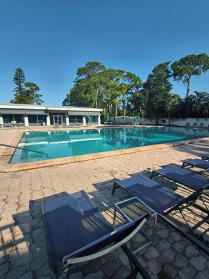Ein Schwimmbecken mit Liegestühlen und einem Gebäude im Hintergrund.