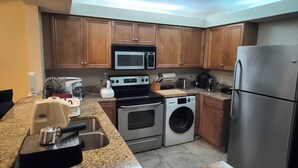 A kitchen with wooden cabinets, a stainless steel refrigerator, a microwave, an oven, a washing machine, and a coffee maker. - Spacious 1 bedroom apartment in awesome Sarasota with swim pool and fitness room (Sarasota)