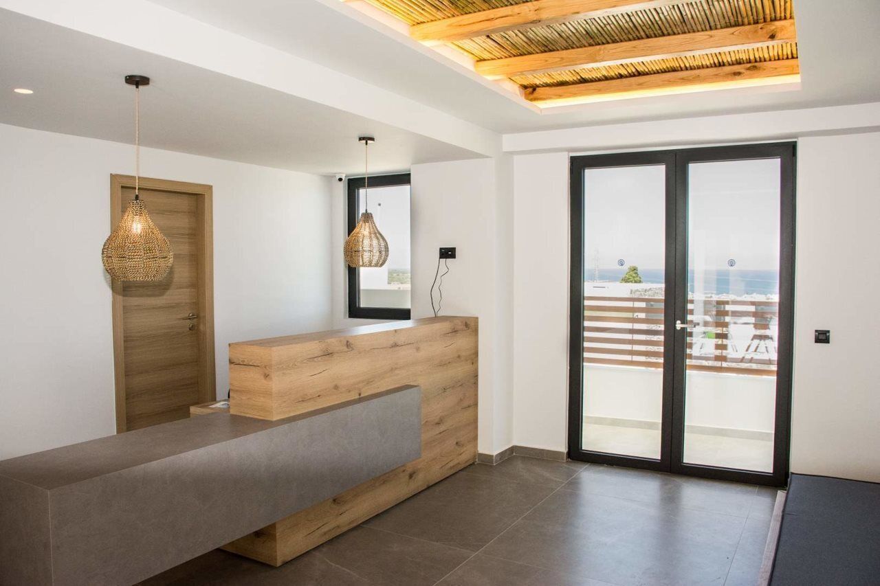 A reception area with a wooden reception desk, two hanging pendant lights, and a view of the outdoors through a glass door.