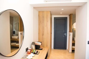 A modern bathroom with a large mirror, a wooden panel wall, a dark door, and a countertop with toiletries.
