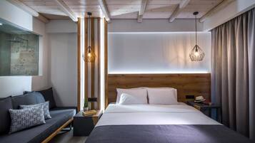 A modern hotel room with a large bed, a sofa, and a wooden headboard.