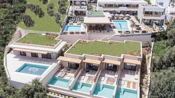 Un hotel moderno con múltiples piscinas, terrazas en la azotea y un jardín ajardinado.