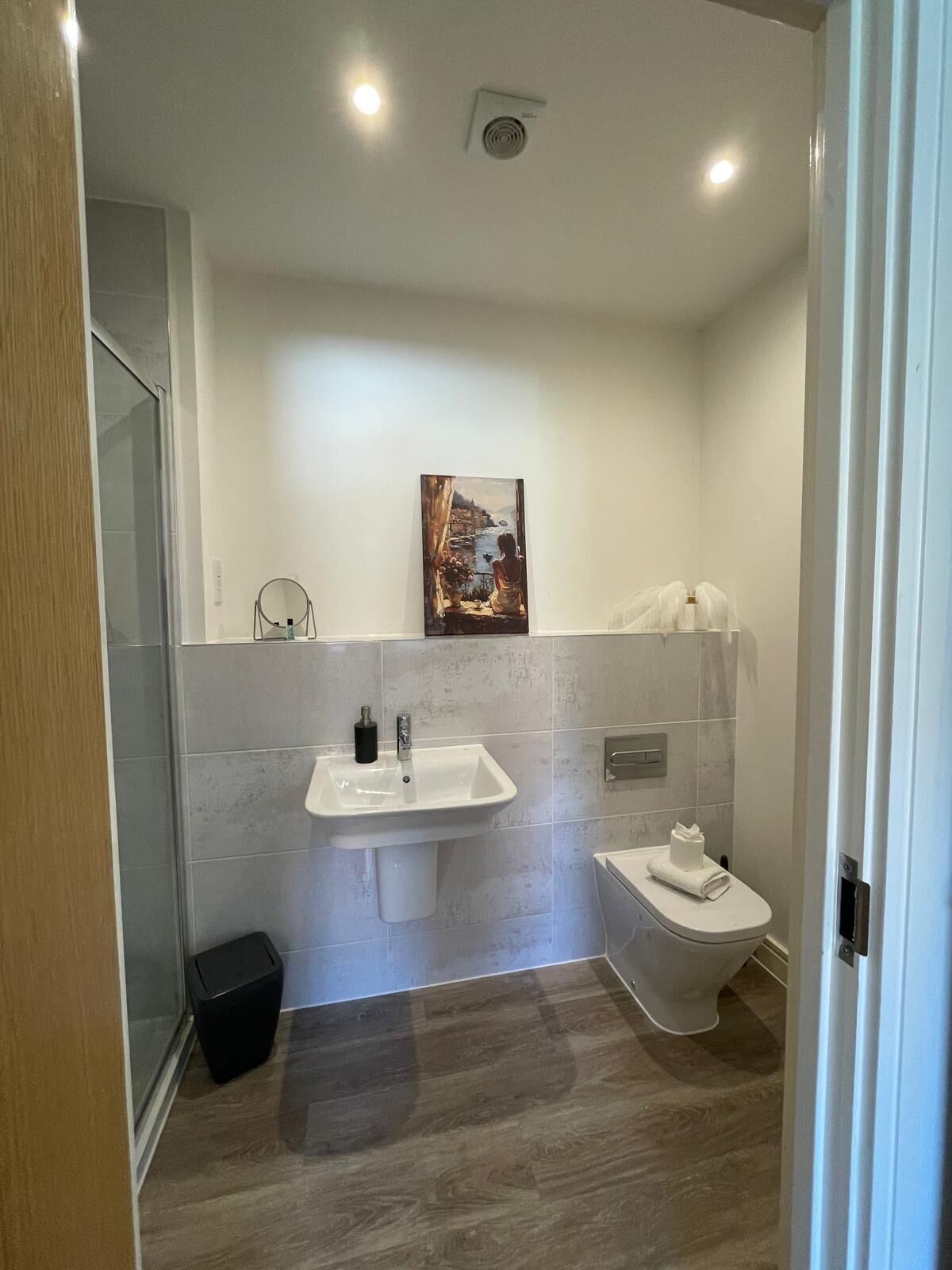 A bathroom with a sink, toilet, and a painting on the wall.