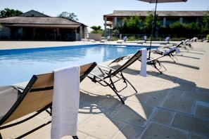 A poolside area with lounge chairs and a tiled deck. - Olydea Le Chateau De Jouarres (Azille)