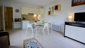 Um espaço compacto com cozinha compacta, área de refeições e uma TV em um suporte.