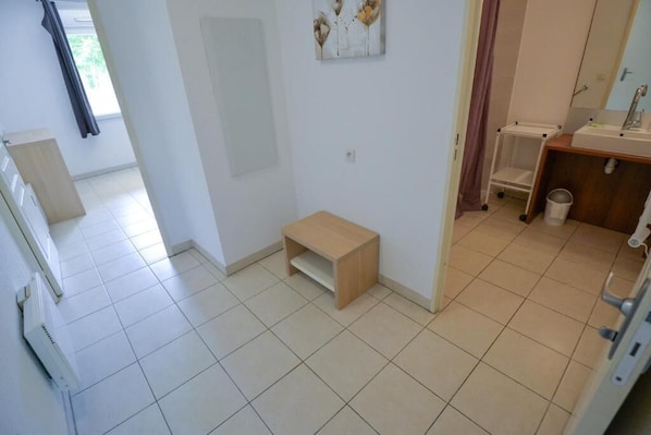 Un baño con lavamanos, espejo y un taburete de madera.