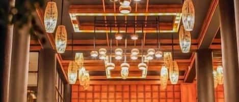 A warmly lit interior with a traditional wooden facade, multiple hanging light fixtures, and a window with a view.