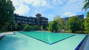 A swimming pool with a clear blue water surface, surrounded by trees and a building with a modern architectural style. - Covanro Sigiriya (Avudangawa)