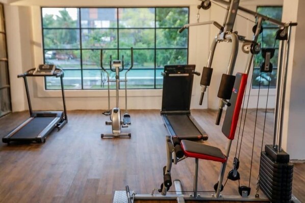 Un gimnasio con cintas de correr, una máquina de remo y una prensa de banca.