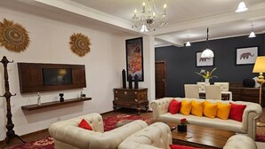 A living room with a television, sofa, armchairs, and a chandelier. - Covanro Sigiriya (Avudangawa)