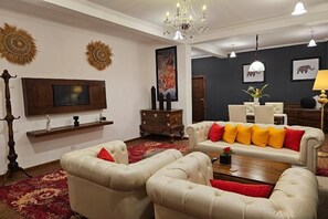 Una sala de estar con televisor, sofá, sillones y una araña.