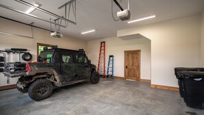 Eine geräumige Garage mit einem großen Geländewagen, einer Leiter und einer Holztür.