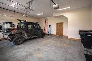 Eine geräumige Garage mit einem großen Geländewagen, einer Leiter und einer Holztür.