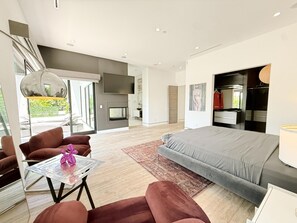 A modern bedroom with a large bed, a TV mounted on the wall, and a fireplace. - Modern Museum 5-bedroom infinity pool (Los Angeles)