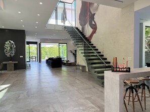 A spacious living area with a modern staircase, a large window, and a minimalist design. - Modern Museum 5-bedroom infinity pool (Los Angeles)