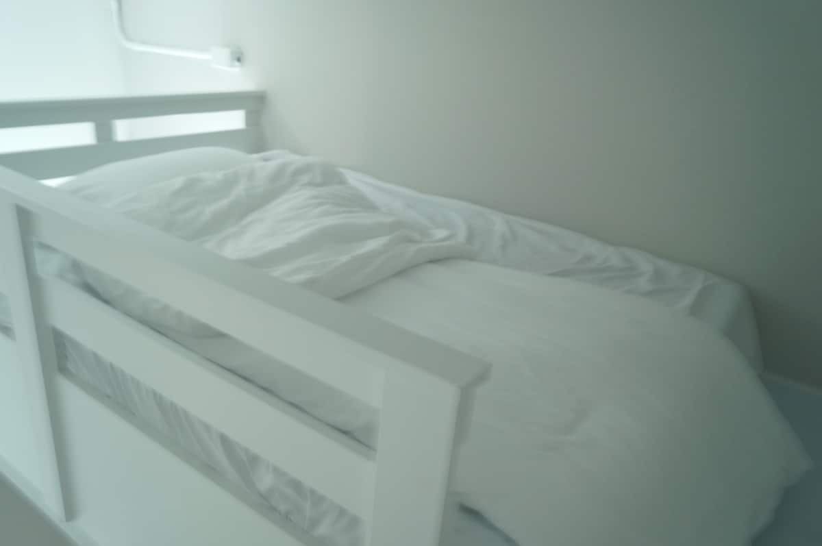 A single bed with a white headboard and a white mattress.
