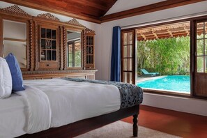 A bedroom with a large bed, wooden headboard, and a view of a swimming pool. - Blusalzz Escapade - Muhamma, Alleppey - Kerala by Zuzu (Cherthala)