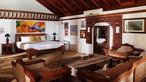 Quarto com cama, móveis de madeira, mesa de jantar e obras de arte nas paredes.