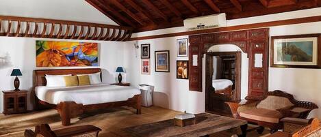 A room with a bed, wooden furniture, a dining table, and artwork on the walls.