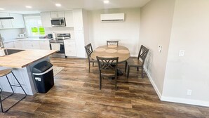 A modern kitchen with white cabinets, a microwave, and a dining area with a wooden table and chairs. - Teton View Farm Stay—Newly remodeled whole home! 3 spacious bedrooms, 2 baths (Unknown)