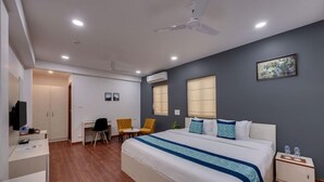 Une chambre d’hôtel équipée d’un lit, d’un bureau, de chaises, d’un ventilateur de plafond et d’un appareil de climatisation.