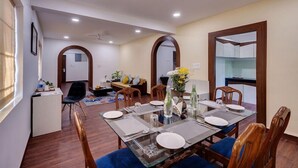 A dining area with a glass table, wooden chairs, and a ceiling fan. - De Garland, Palolem - AM Hotel Kollection (Canacona)