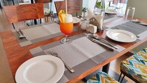 Une table à manger dressée avec un verre de jus d’orange, une bouteille d’eau et un salier et un poivrier.