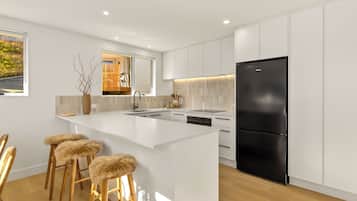 A modern kitchen with white cabinetry, a black refrigerator, and a central island with bar stools.