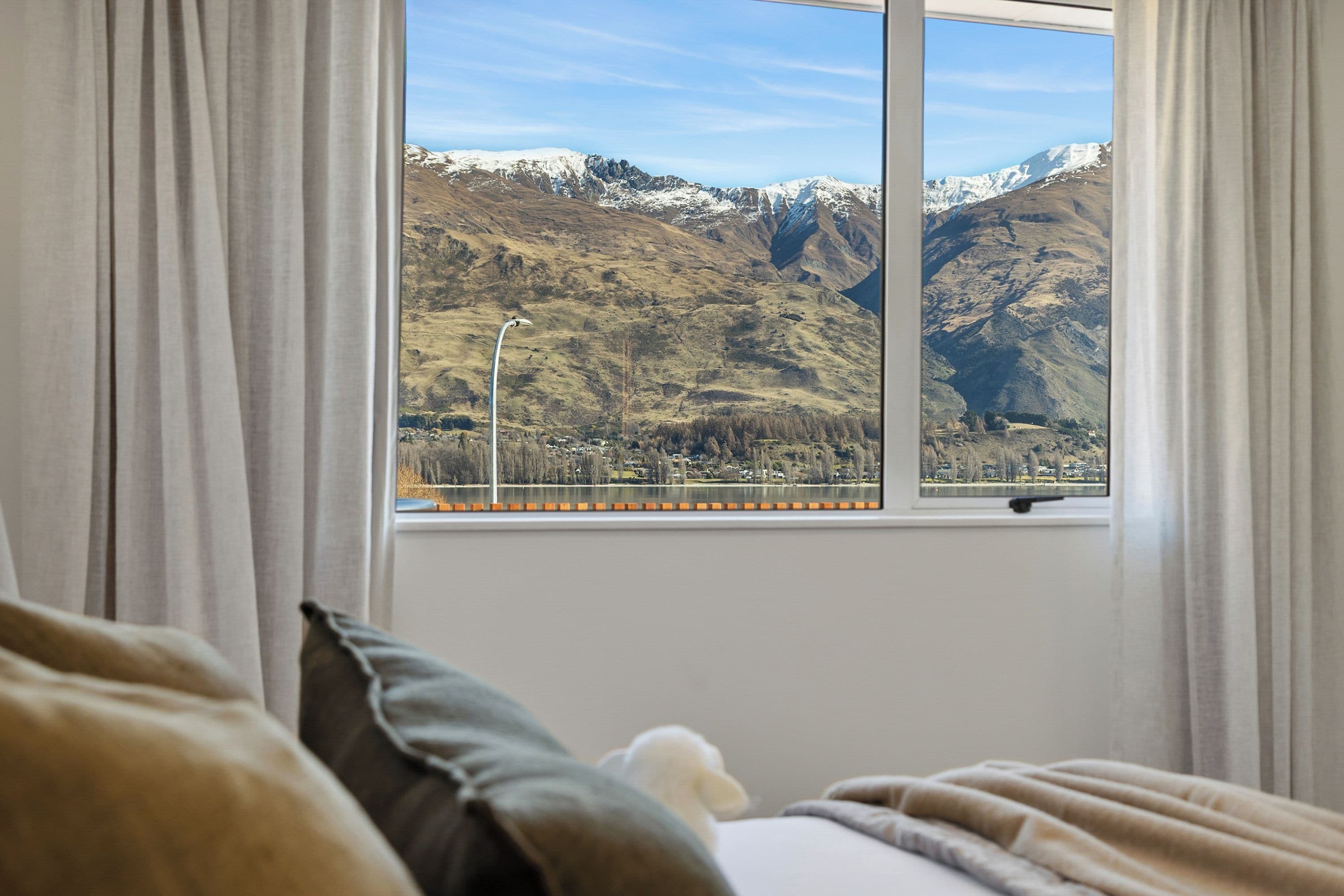 A bedroom with a window overlooking a mountainous landscape.