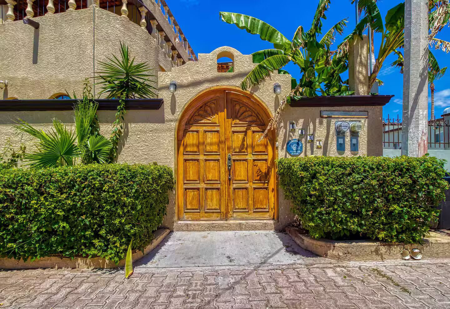 A traditional building with a large wooden door, a stone wall, and a clear blue sky.