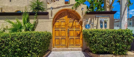 A traditional building with a large wooden door, a stone wall, and a clear blue sky.