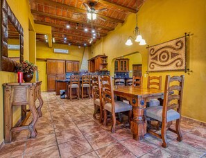 A dining area with a wooden table and chairs, a ceiling fan, and a decorative wall hanging. - Ocean views, close to beach and marina boardwalk! (San Carlos Nuevo Guaymas)