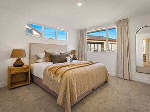 Un dormitorio con cama, mesitas de noche, una ventana con cortinas y un espejo.