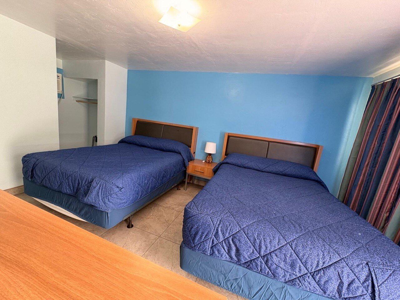 A hotel room with two beds, a nightstand, and a bathroom door.