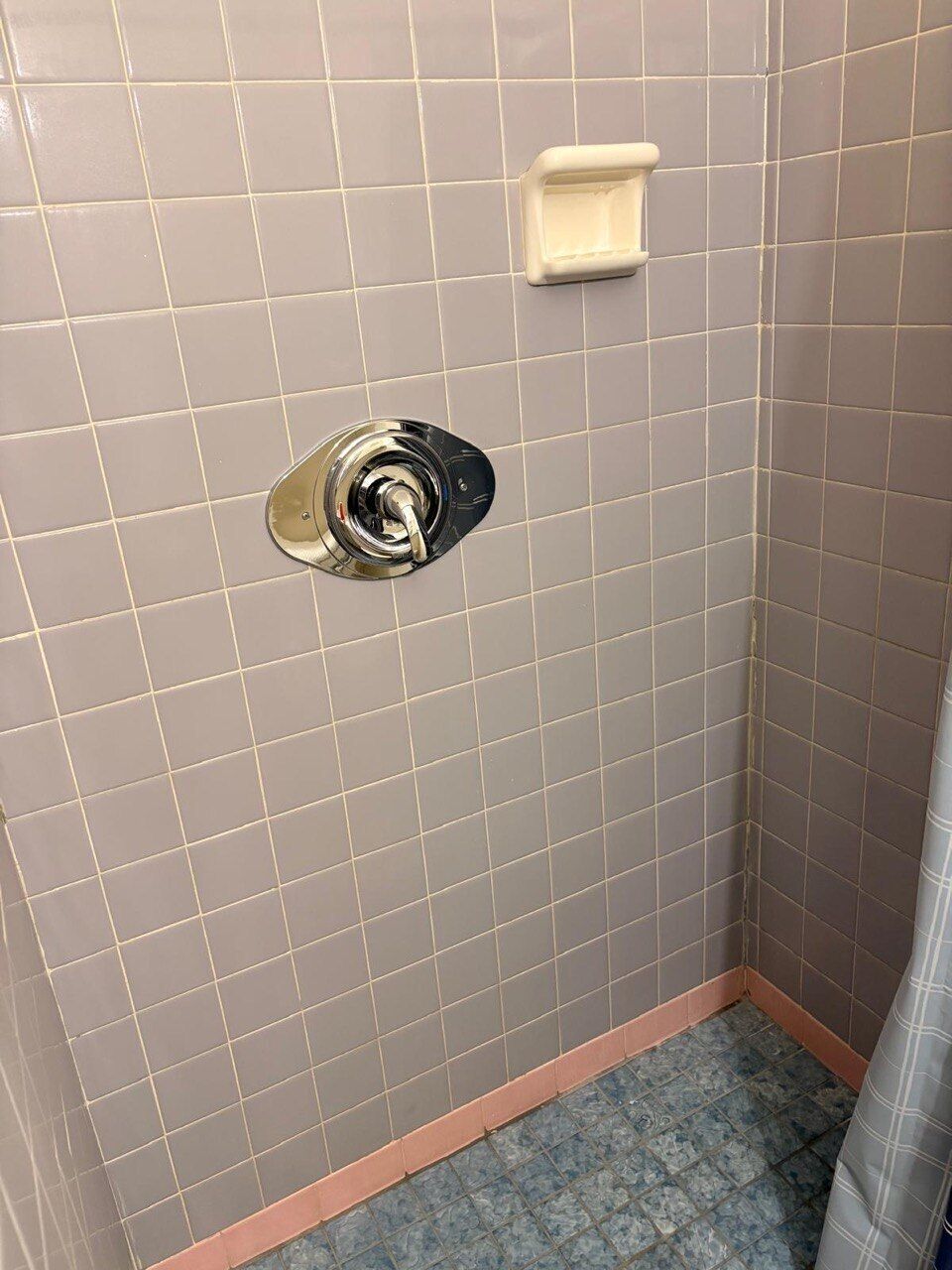 A bathroom with a tiled floor, a shower area, and a toilet.