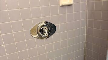 A bathroom with a tiled floor, a shower area, and a toilet.