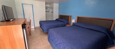 A hotel room with two beds, a desk, and a television.