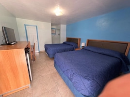 Una habitación de hotel con dos camas, un escritorio y una televisión.